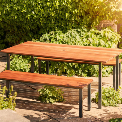 Hardwood Garden Table & Benches. The table is empty and has a hole for a parasol. Made from durable Sapele hardwood and placed on a garden patio,