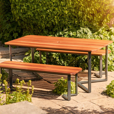 Hardwood Outdoor Dining Set. The table is empty and has a hole for a parasol. Made from durable Sapele hardwood and placed on a garden patio.