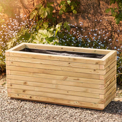 Large rectangular garden planter in a natural finish, lined for added functionality. This durable wooden planter features a modern, sleek design and is placed against a wall with climbing green plants.