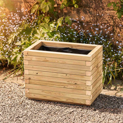 Medium rectangular garden planter in a natural finish, lined for added functionality. This durable wooden planter features a modern, sleek design and is placed against a wall with climbing green plants.