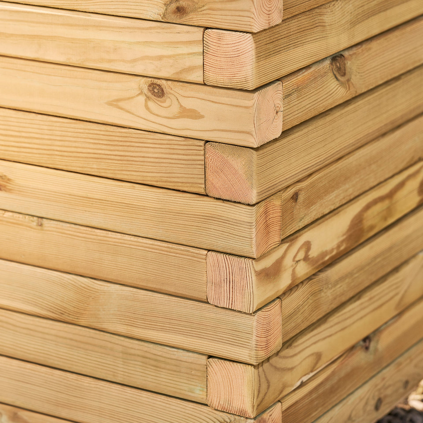 A close-up corner view of a rectangular wooden garden planter filled with yellow flowers and green plants. The durable timber planter has a modern, sleek design and is placed in a garden.