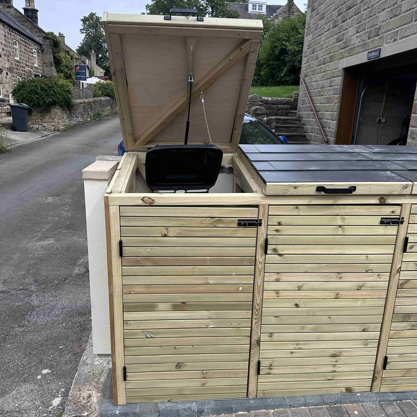 Wooden outdoor storage unit and bin store. Open lid showing bin inside.