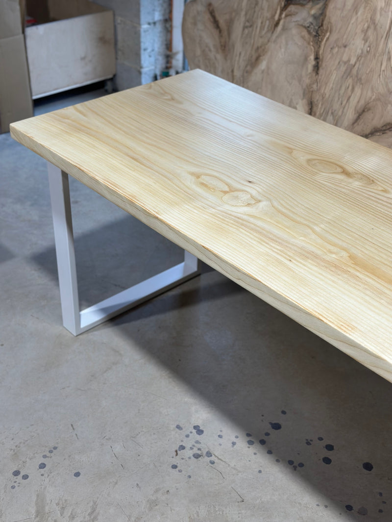 A solid English ash tabletop on a white steel frame in the workshop
