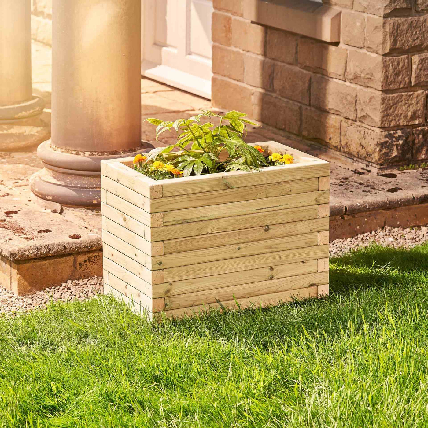 A medium rectangular wooden garden planter filled with yellow flowers and green plants. The durable timber planter has a modern, sleek design and is placed in a garden.