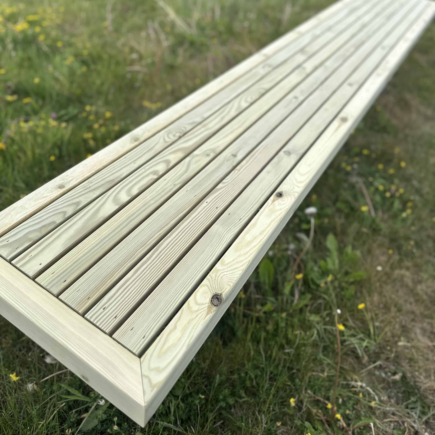 Wooden garden dining set with full-length benches and steel X legs, ideal for gardens and patios. Full length bench closeup shown on grass area.