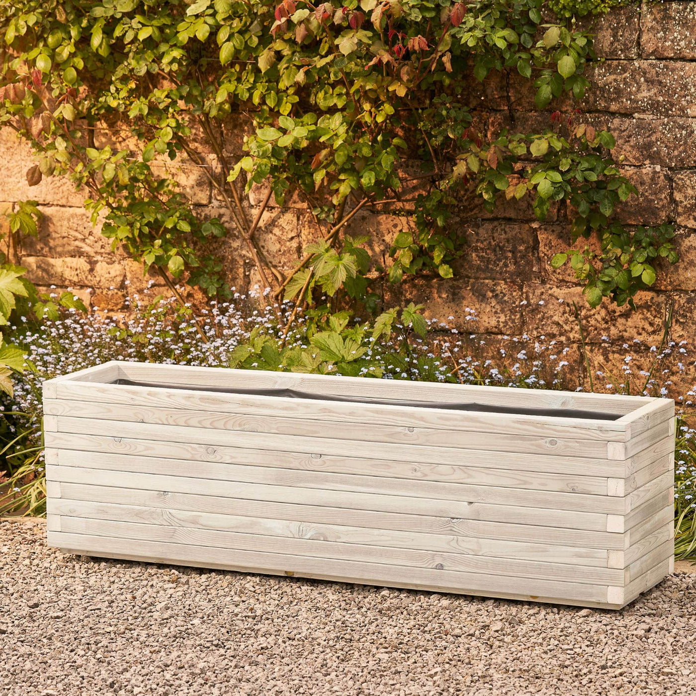 XXL rectangular garden planter in a soft white finish, lined for added functionality. This durable wooden planter features a modern, sleek design and is placed against a wall with climbing green plants.