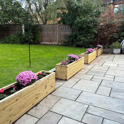 Customer's garden featuring modern wooden planters purchased from Timber Foundry, filled with vibrant flowers.